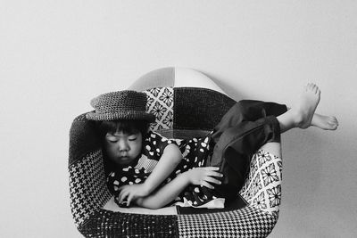Boy wearing hat sleeping on chair against wall at home