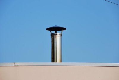 Low angle view of pipe against clear blue sky