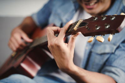 Midsection of man playing guitar