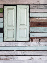 Old grunged wooden window frame painted white vintage with old colourful plywood wall. 