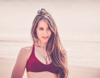 Close-up of smiling young woman standing at beach