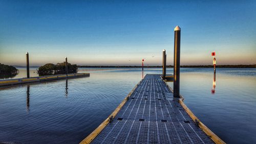 Pier over sea against clear blue sky