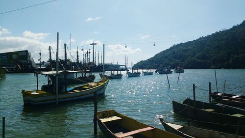 Boats moored at harbor against sky