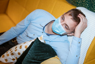 Young guy sitting on the couch wearing a medical mask