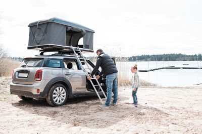 Father and daughter setting up a roof top tent for social distancing