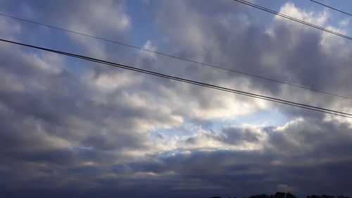 Low angle view of cables against dramatic sky