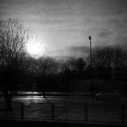 Cars on road against cloudy sky at dusk