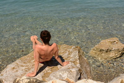 Woman sitting on rock by sea