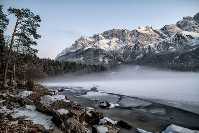 Scenic view of frozen lake by mountains against sky