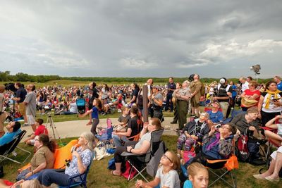 Crowd of people sitting at town square against sky