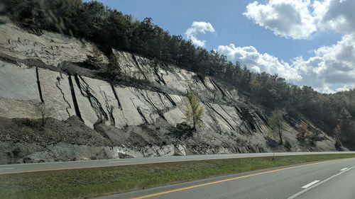 Road by trees against sky