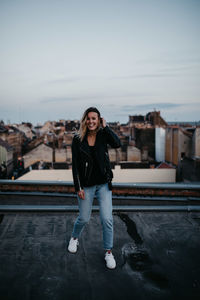 Portrait of young woman standing against sky