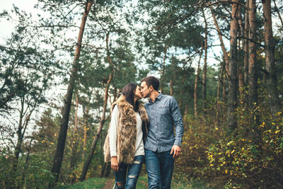 Young couple kissing while walking in forest