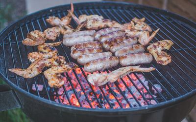 Close-up of chicken wings and sausages on barbecue grill