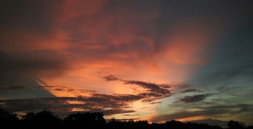 Low angle view of silhouette trees against dramatic sky