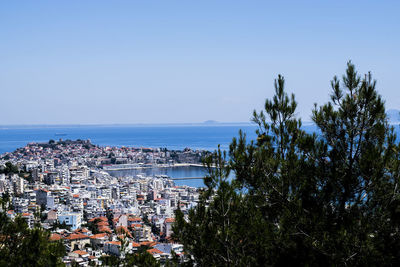 Aerial view of townscape by sea against clear sky