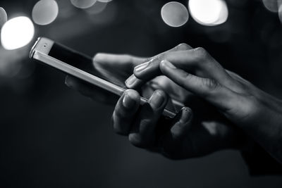 Cropped hands of man using phone at night