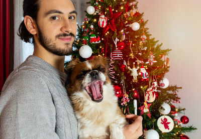 Portrait of man with dog on christmas tree