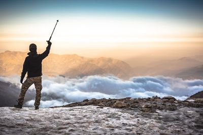 Man standing on snow covered mountain against sky