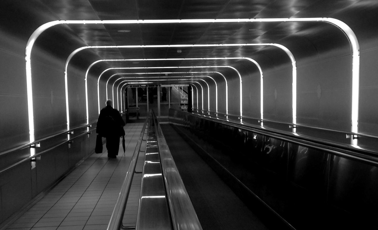 indoors, rear view, walking, men, full length, the way forward, lifestyles, subway, person, tunnel, transportation, railroad track, illuminated, railing, escalator, architecture, railroad station, diminishing perspective