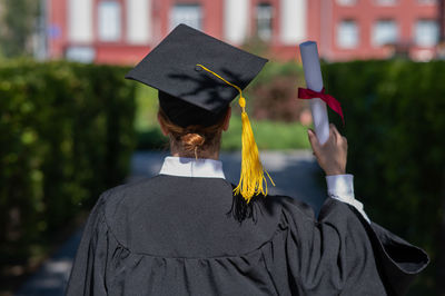 Portrait of woman wearing graduation gown standing outdoors