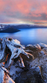 Scenic view of frost on landscape surrounding calm sea at sunset