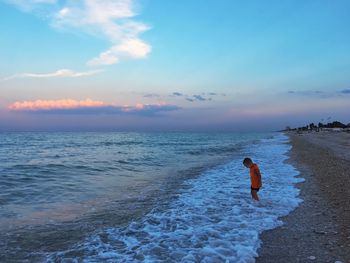 Side view of boy standing on shore at beach