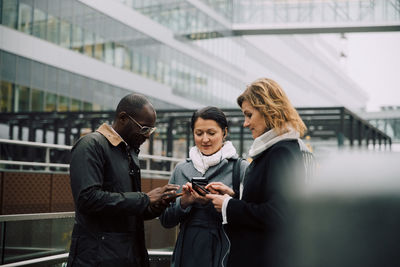 Young woman using mobile phone while standing on laptop