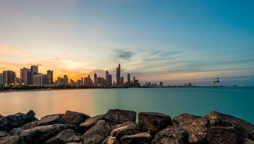 Scenic view of sea and buildings against sky during sunset