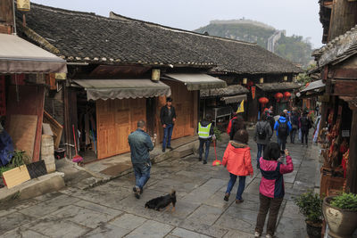 People walking outside houses against buildings