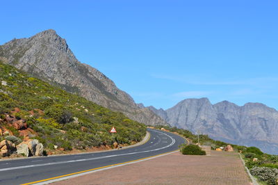 Road amidst mountains against clear blue sky