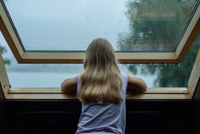 Rear view of woman looking through window