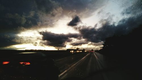 Cars on road against dramatic sky at night