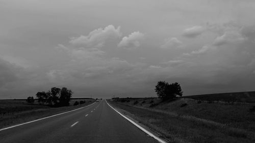 Road amidst field against sky