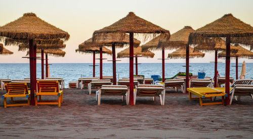 Deck chairs on beach against clear sky