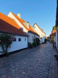 Footpath amidst houses in town against clear sky