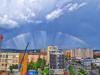 Rainbow over buildings in city against sky