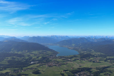 Aerial view of landscape and mountains against blue sky