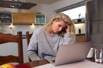 Frustrated woman looking in laptop at table