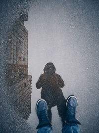 Low section of man standing on puddle