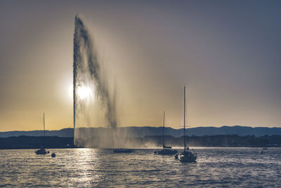 Sailboat sailing on lake against sky during sunset