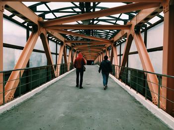 Rear view of people walking on footbridge