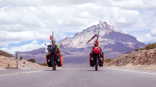 Rear view of people riding motorcycle on road