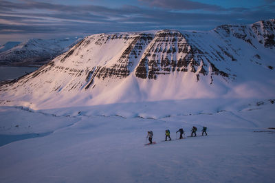 Group of people backcountry skiing at sunrise in iceland