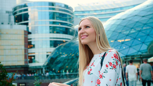 Portrait of young woman standing against buildings