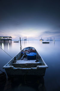 Boat moored in sea at sunset