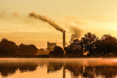 Smoke emitting from smoke stack by lake