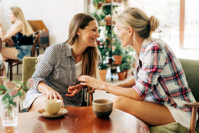 Two young slim women sitting in a coffee shop having fun chatting.