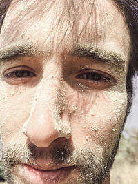 Close-up portrait of shirtless dirty young man at beach