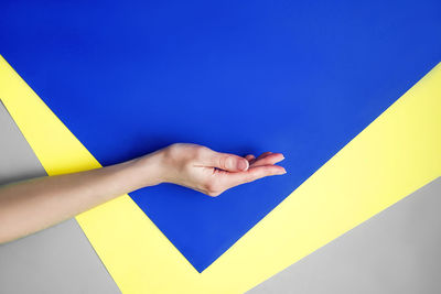 Close-up of hand against blue wall